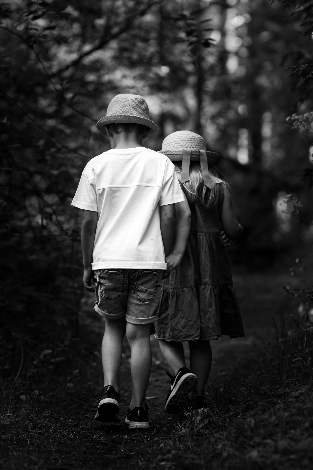 Two children in hats walking in the woods