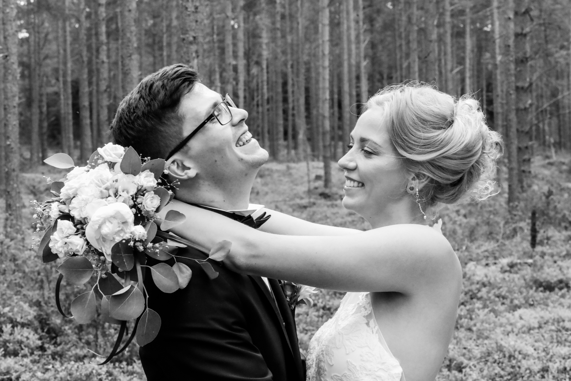 Couple laughing in a forest with bouquet